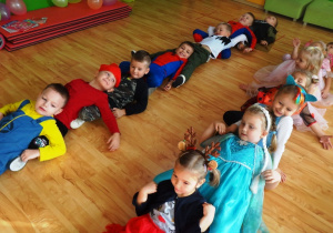 Dzieci siedzą na podłodze w bajkowych strojach